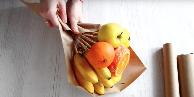 Βάλτε ένα σωρό φρούτα με τα χέρια σας διαγώνια το χαρτί και τυλίξτε το κάτω μέρος